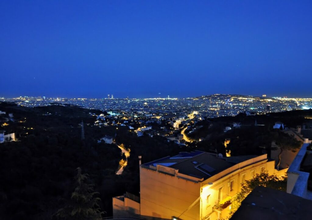 Vue de Barcelone à la tombée de la nuit depuis les hauteurs : la ville éclairée sous un ciel encore bleu profond