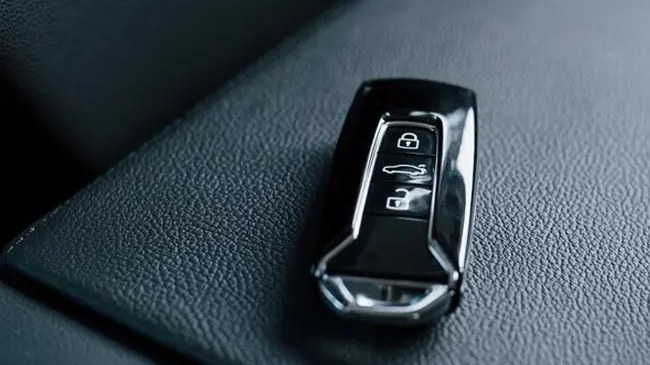 Une clé de voiture électronique posée sur un siège en cuir