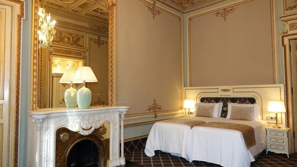 Chambre de l'Hôtel Continental Palacete, lits jumeaux, cheminée en marbre et dorures