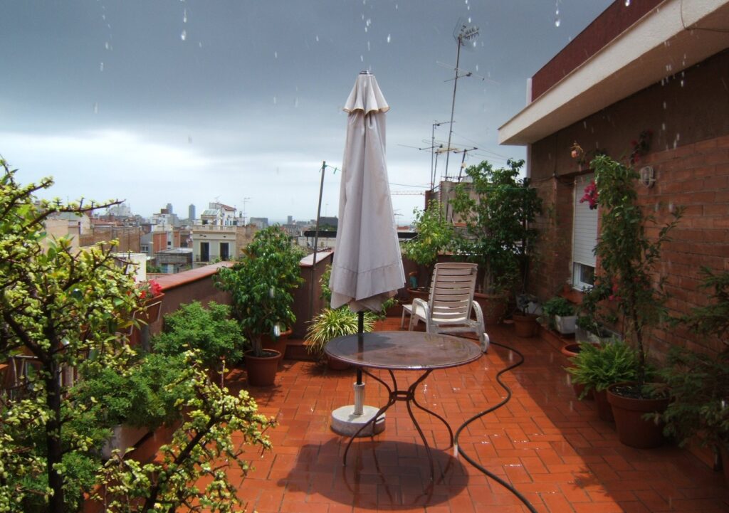 Une terrasse fleurie sur les toits de Barcelone sous une averse